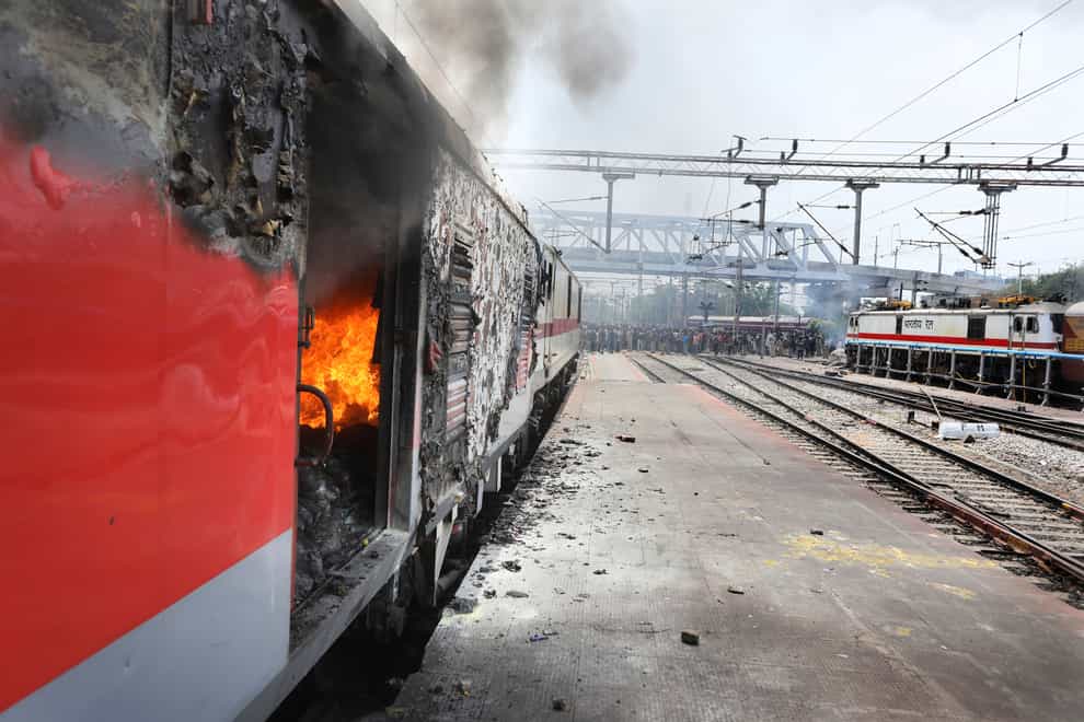 Flames rise from a train set on fire by protestors at a Secundrabad railroad station in Hyderabad, India, Friday, June 17, 2022. Hundreds of angry youths gave vent to their ire by burning train coaches, vandalizing railroad property and blocking rail tracks and highways with boulders as a backlash continued for a second straight day Friday against a new short-term government recruitment scheme for the military. Nearly 500 protesters vastly outnumbered policemen as they went on a rampage for more than an hour at Secundrabad railroad station in southern India. (AP Photo/Mahesh Kumar A)