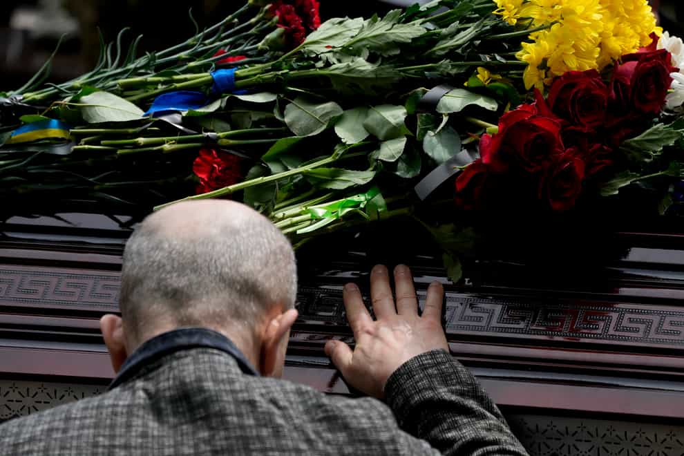 A man touches the coffin of activist and soldier Roman Ratushnyi during his funeral in Kyiv (AP)