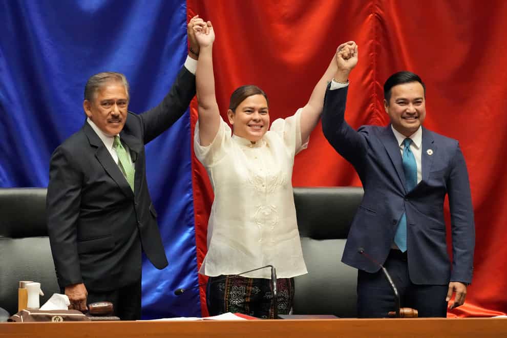 Vice president-elect Sara Duterte, centre, raises her hands with Senate President Vicente Sotto III, left, and House Speaker Lord Allan Velasco during her proclamation at the House of Representatives (Aaron Favila/AP)