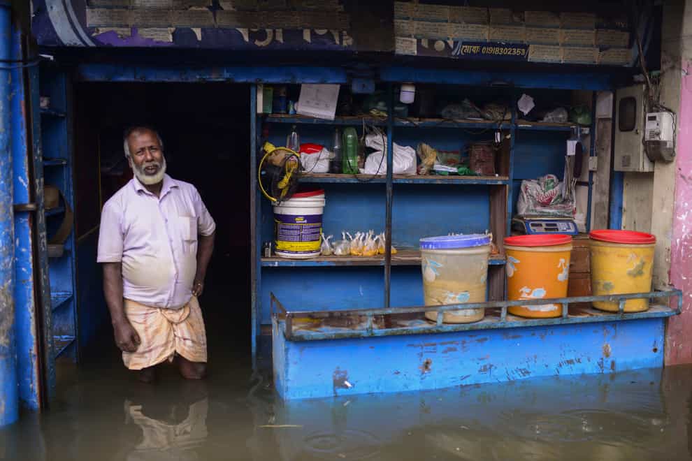 A man stands at the doorway of his flooded shop in Sylhet (Mahmud Hossain Opu/AP)