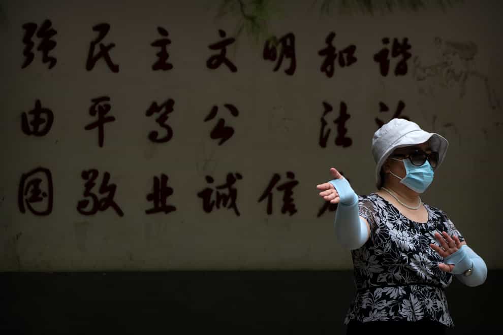 A woman wearing a face mask exercises at a public park in Beijing (Mark Schiefelbein/AP)