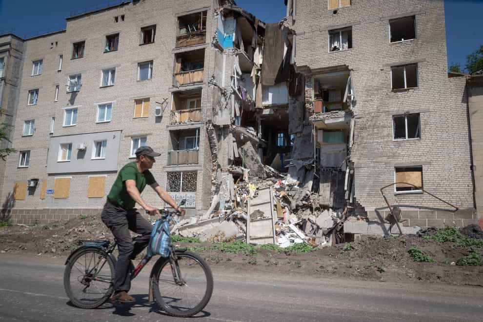 A man rides a bicycle past a building damaged in Russian shelling in Bakhmut, Donetsk region, Ukraine (Efrem Lukatsky/AP)