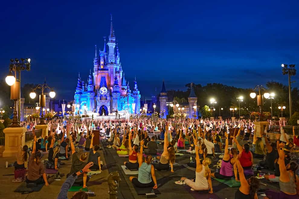 Nearly 2,000 cast members practise sunrise yoga celebrating International Yoga Day in front of Cinderella Castle at the Magic Kingdom Park at Walt Disney World in Lake Buena Vista, Florida (John Raoux/AP)