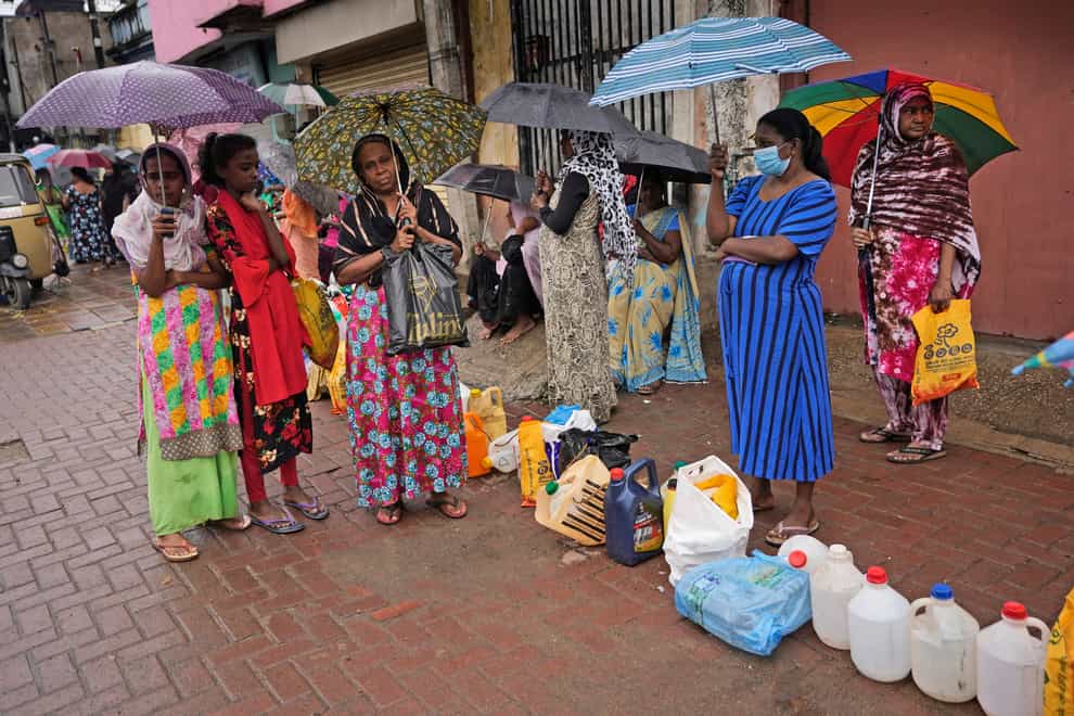 Women wait in a queue to buy fuel in Colombo (AP)