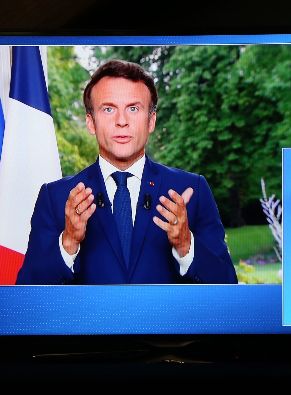 French President Emmanuel Macron appears on a screen as he gives a national televised address (Bob Edme/AP)