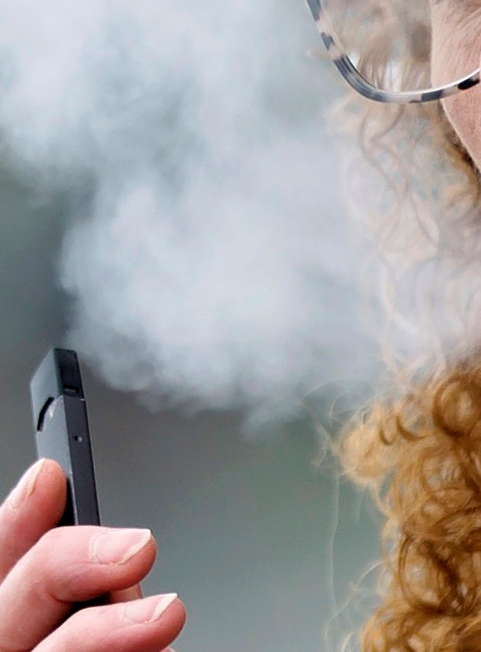 A woman exhales while vaping from a Juul pen e-cigarette(Craig Mitchelldyer/AP)