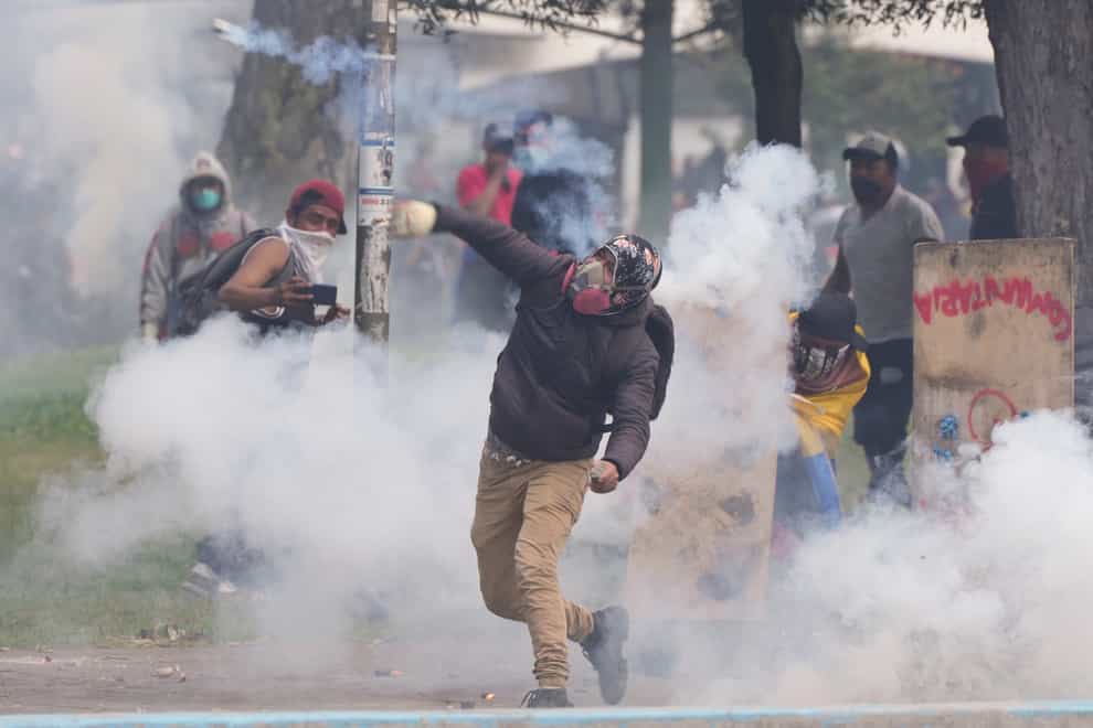 A demonstrator hurls a tear gas canister back at police during protests against the government of President Guillermo Lasso and rising fuel prices in Quito, Ecuador (Dolores Ochoa/AP)