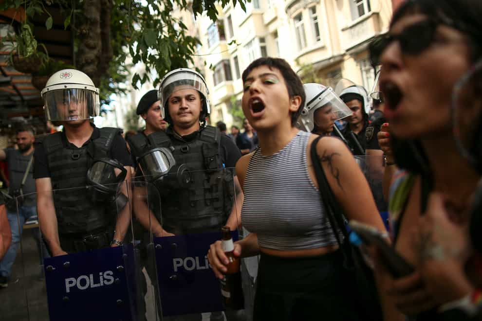 People shout slogans next to Turkish police officers during the LGBTQ Pride March in Istanbul (Emrah Gurel/AP)