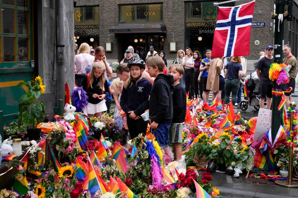 People lay flowers at the scene of a shooting in central Oslo, Sergei Grits/AP)