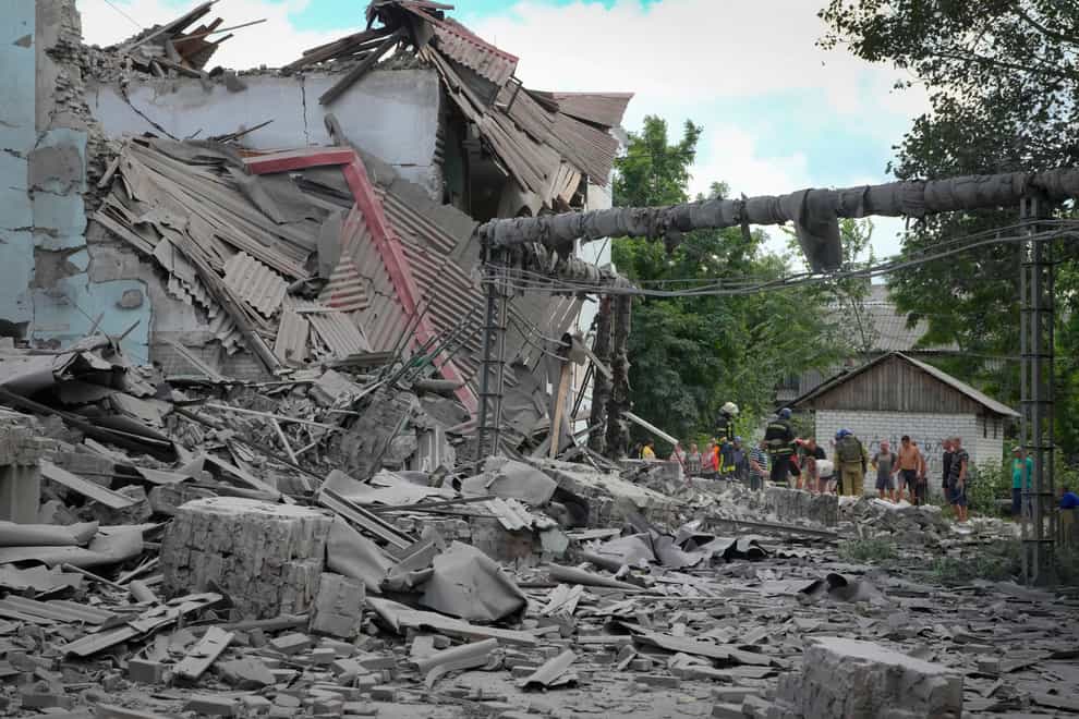 Search and rescue workers and local residents take a dead body from under the debris of a building after the Russian air raid in Lysychansk, Luhansk region, Ukraine, Thursday, June 16, 2022. (AP Photo/Efrem Lukatsky)