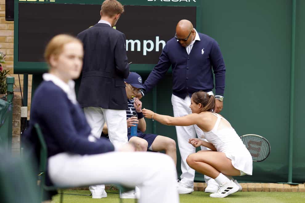Jodie Burrage helps a ball boy after he fell unwell during her loss to Lesia Tsurenko (Steven Paston/PA)