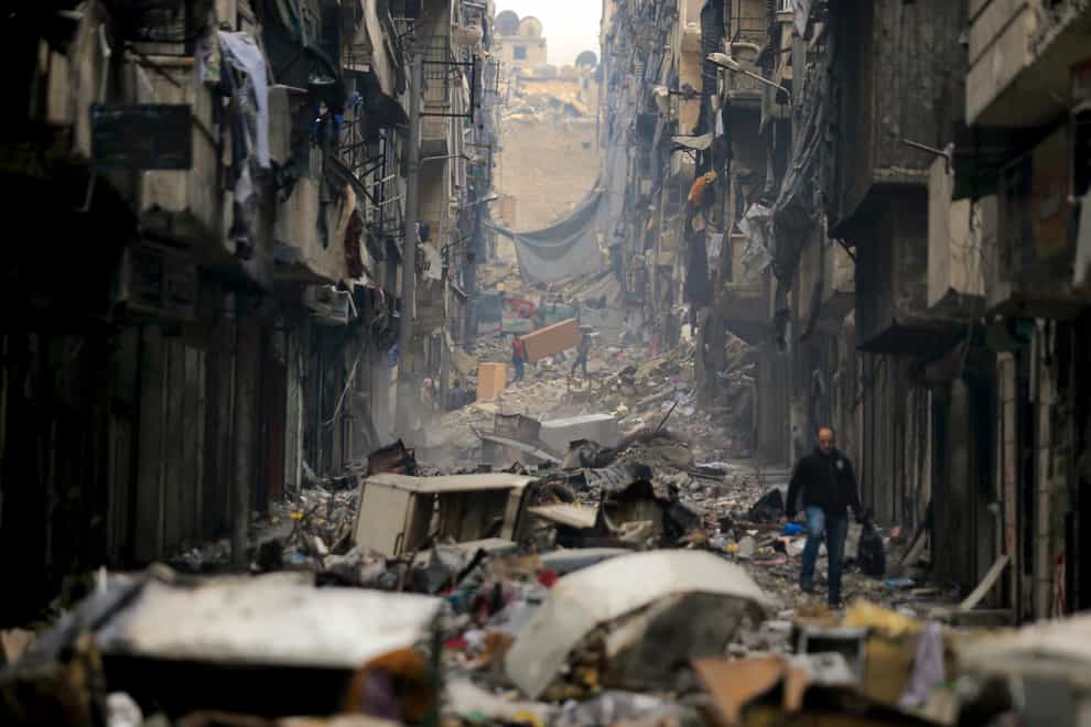 Residents walk through the destruction of the once rebel-held Salaheddine neighbourhood in the eastern Aleppo, Syria (AP)
