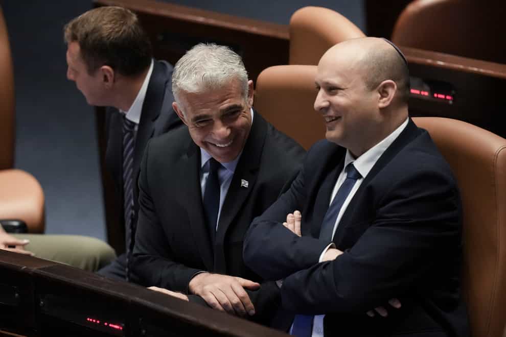 Israeli Prime Minister Naftali Bennett, right, and foreign minister Yair Lapid smile ahead of the vote on a bill to dissolve parliament, at the Knesset (AP)