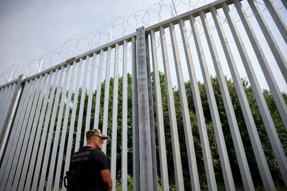 A Polish border guard patrols the area near the new wall (Michal Dyjuk/AP)