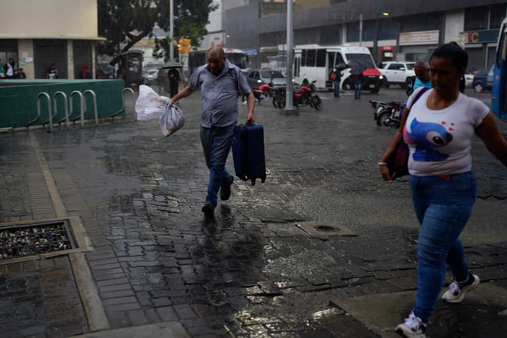 A man runs from the rain in Caracas, Venezuela (Ariana Cubillos/AP)