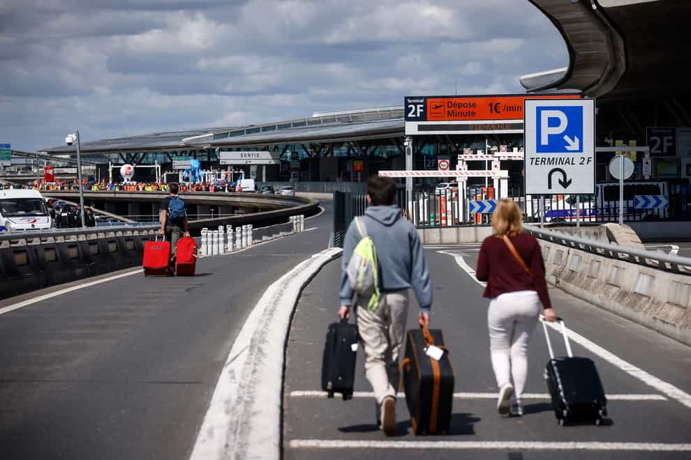 Travelers arrive on foot at Roissy-Charles de Gaulle airport while airport workers demonstrate (Thomas Padilla/AP)