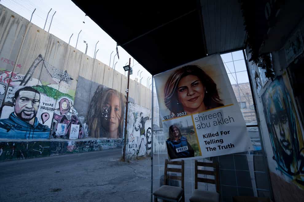 Slain Palestinian-American journalist Shireen Abu Akleh is depicted in a poster near murals of George Floyd, a black American killed by police in Minneapolis in 2020, and Palestinian activist Ahed Tamimi, centre, on Israel’s controversial separation barrier in the West Bank town of Bethlehem (Maya Alleruzzo/AP)
