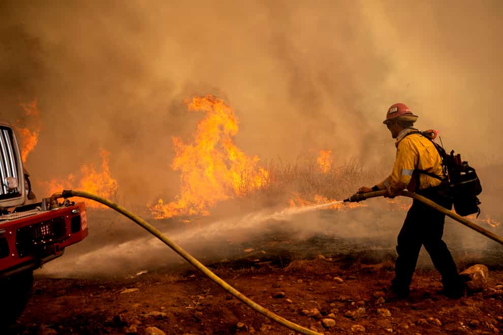 A firefighter sprays water while trying to keep the Electra Fire from spreading in the Pine Acres community of Amador County (AP)