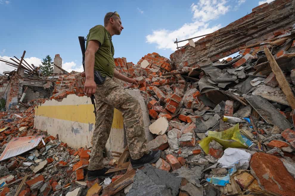 A Ukrainian serviceman looks at the rubble of a school that was destroyed some days ago during a missile strike in outskirts of Kharkiv (AP)