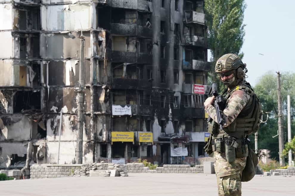 A member of the Ukrainian military stands in front of damaged buildings in the Borodyanka area of Kyiv (Niall Carson/PA)