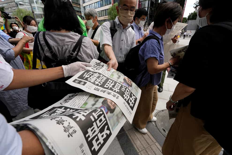 An employee distributes extra editions of the Yomiuri Shimbun newspaper reporting on Japan’s former prime Mminister Shinzo Abe being shot (Eugene Hoshiko/AP)