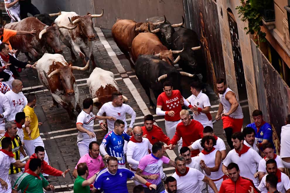 People run in the street with fighting bulls during the San Fermin Festival in Pamplona, northern Spain (Alvaro Barrientos/AP)