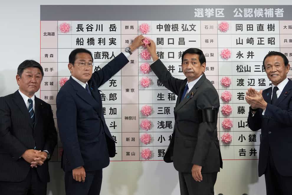 Japan’s prime minister Fumio Kishida, second left, puts a red paper rose on a Liberal Democratic Party candidate’s name to indicate a victory in the upper house election (Toru Hanai, Pool Photo via AP)
