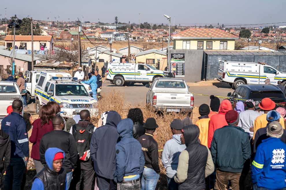 People gather at the scene of an overnight bar shooting in Soweto, South Africa, Sunday July 10, 2022. A mass shooting at a tavern in Johannesburg’s Soweto township has killed 15 people and left others in critical condition, according to police. Police say they are investigating reports that a group of men arrived in a minibus taxi and opened fire on some of the patrons at the bar shortly after midnight Sunday. (AP Photo/Shiraaz Mohamed)