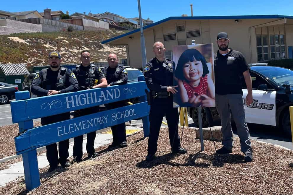 Interim Police Chief Nick Borges, second from right, and Detective Joshua Parker, right, stand next to a photo of Anne Pham outside Highland Elementary School on July 7, 2022 (Seaside Police Department/AP)