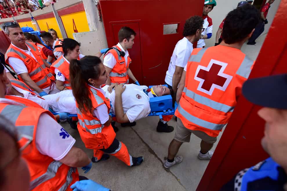 Medics help a runner who got injured when calves were released in the bullring after the running of the bulls at the San Fermin Festival in Pamplona, northern Spain, on Tuesday July 12 2022 (Alvaro Barrientos/AP)