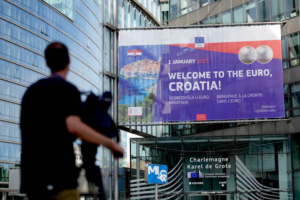 A journalist films a banner welcoming Croatia to the euro in front of EU headquarters in Brussels (Virginia Mayo/AP)