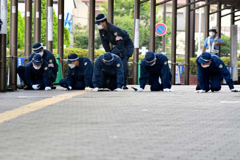 Police inspect a pavement near the site where former Japanese prime minister Shinzo Abe was fatally shot in Nara (Kyodo News/AP)