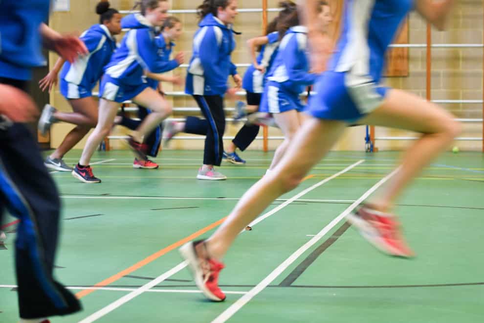 Pupils run during a PE lesson inside a sports hall (PA)