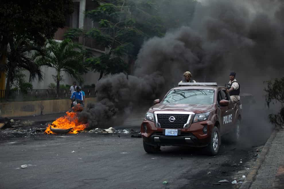 Police drive their car over a barricade set up by taxi drivers to protest fuel shortages in Port-au-Prince, Haiti (AP)