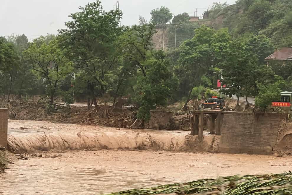 A vehicle near part of a bridge that was washed away by floods along a river in Qingyang in north-west China’s Gansu province (Chinatopix/AP)