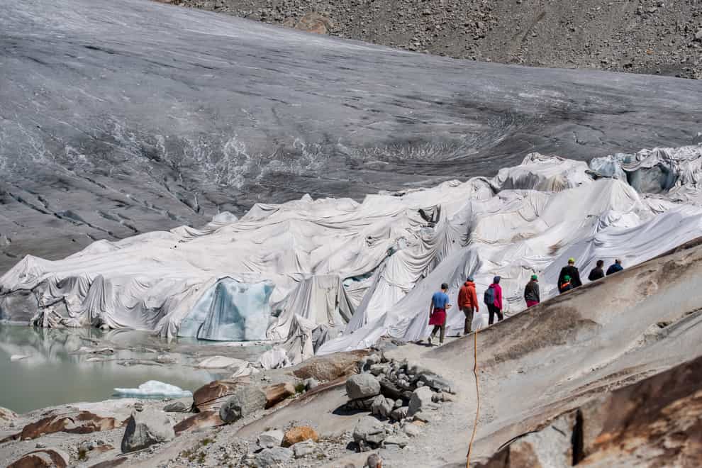 People visit the Rhone Glacier covered in blankets above Gletsch near the Furkapass in Switzerland (Keystone via AP)