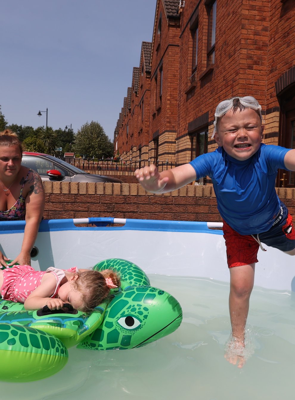 Emma Stewart with her children Caleb, 5, and Isla aged 2, cooling down in a swimming pool at their family home in Ardoyne, north Belfast. Picture date: Monday July 18, 2022.