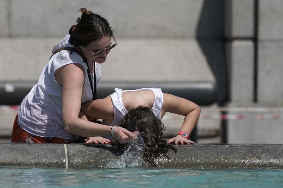 A person wets their hair in a fountain at Trafalgar Square in central London as temperatures hit 40C for the first time ever in the UK (Aaron Chown/PA)