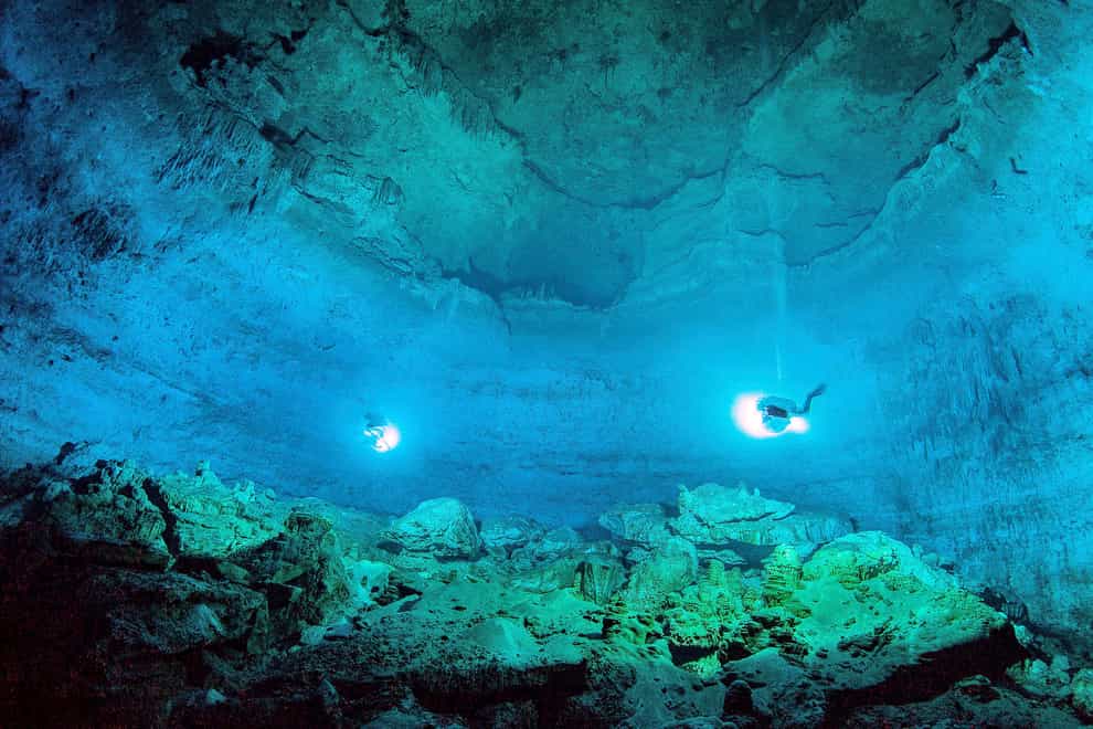 Scuba divers explore the Hoyo Negro underwater cave, or cenote, in Tulum, Quintana Roo state, Mexico, where according INAH, a skeleton almost 13,000 years old of a prehistoric young woman was found, making it the oldest and most complete found in the Americas. The Mexican government invoked national-security powers on July 18, 2022 to forge ahead with a tourist train along the Caribbean coast, while activists warn the high-speed rail project will fragment the coastal jungle and run above the roofs of fragile limestone cenotes (Mexico’s National Institute of Anthropology and History/AP/PA)