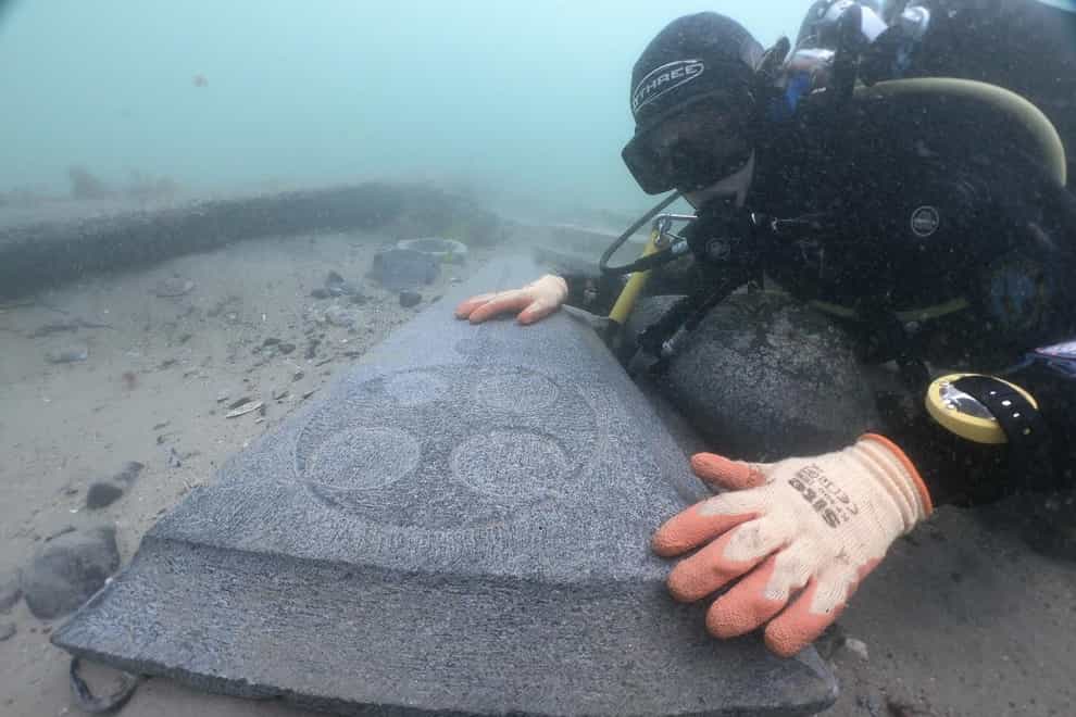 A diver looks at decorated gravestone near the Mortar wreck (Bournemouth University/PA)