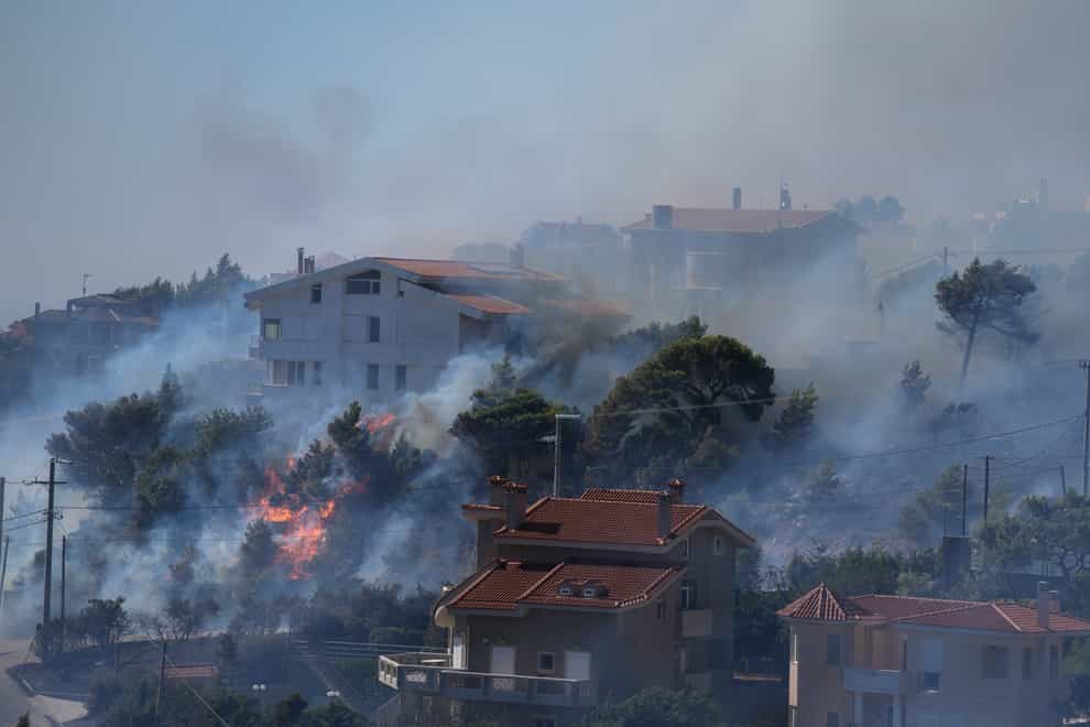 Fire burns next to houses in the area of Drafi east of Athens (Thanassis Stavrakis/AP)