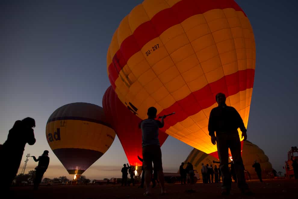 Tourists watch hot air balloons prepare to take off at dawn on the west bank of the Nile River in Luxor, Egypt (Amr Nabil/AP)