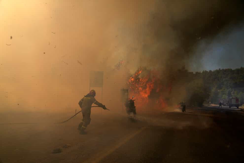 A firefighter tries to extinguish the flames next to motorcycles during a wildfire near Megara town, west of Athens, Greece (Petros Giannakouris/AP)