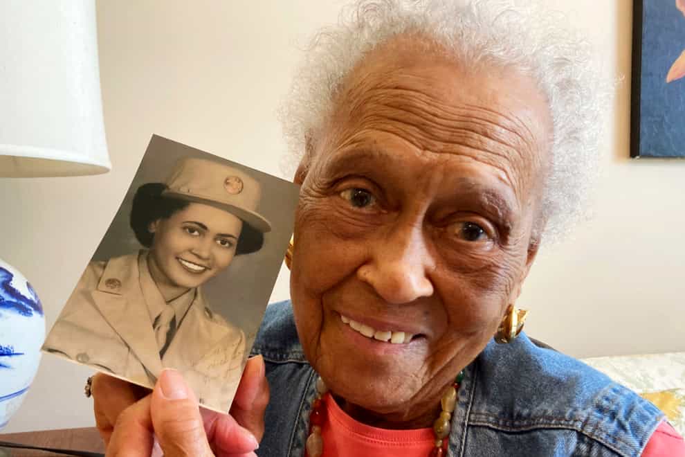 Romay Davis, 102, poses with a photo showing her during the Second World War, at her home in Montgomery, Alabama (Jay Reeves/AP)