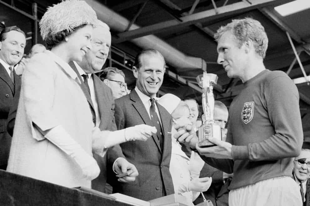 Captain Bobby Moore, right, receives the World Cup trophy from the Queen, left, in 1966 (PA)
