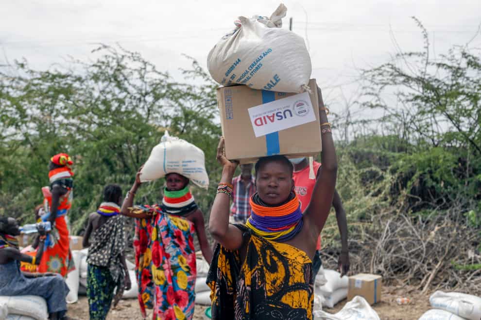 Local residents carry boxes and sacks of food distributed by the United States Agency for International Development in Kachoda, Turkana area, northern Kenya (Desmond Tiro/AP)