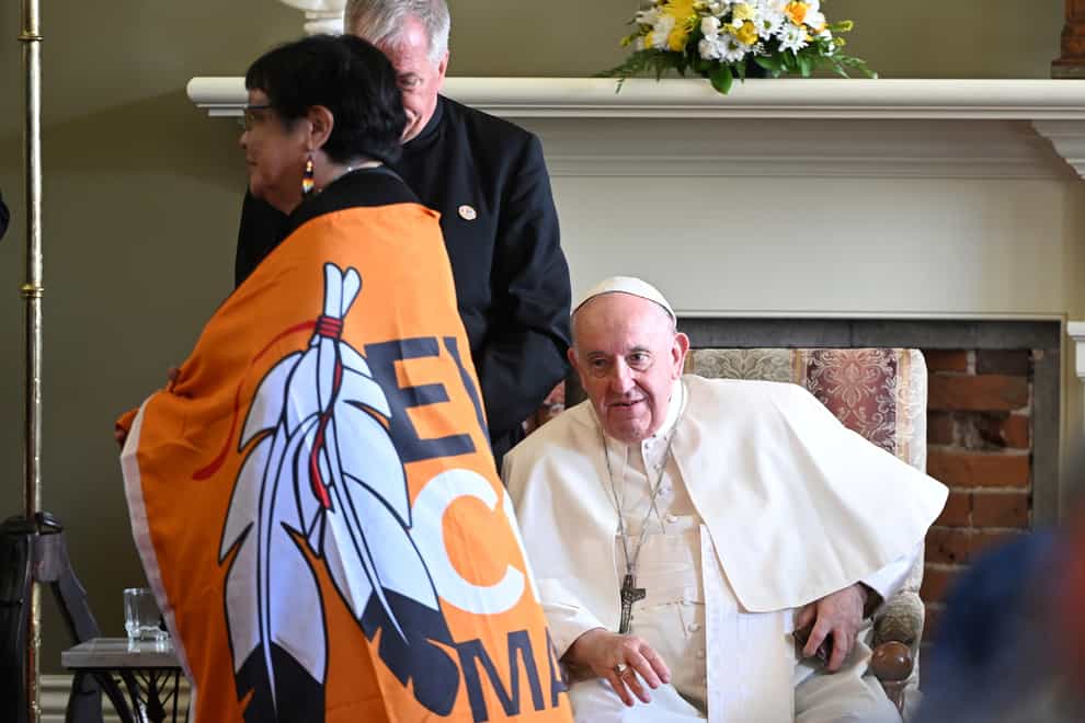 Pope Francis looks at a woman wearing a flag with the slogan Every Child Matters (Jacques Boissinot/The Canadian Press via AP)