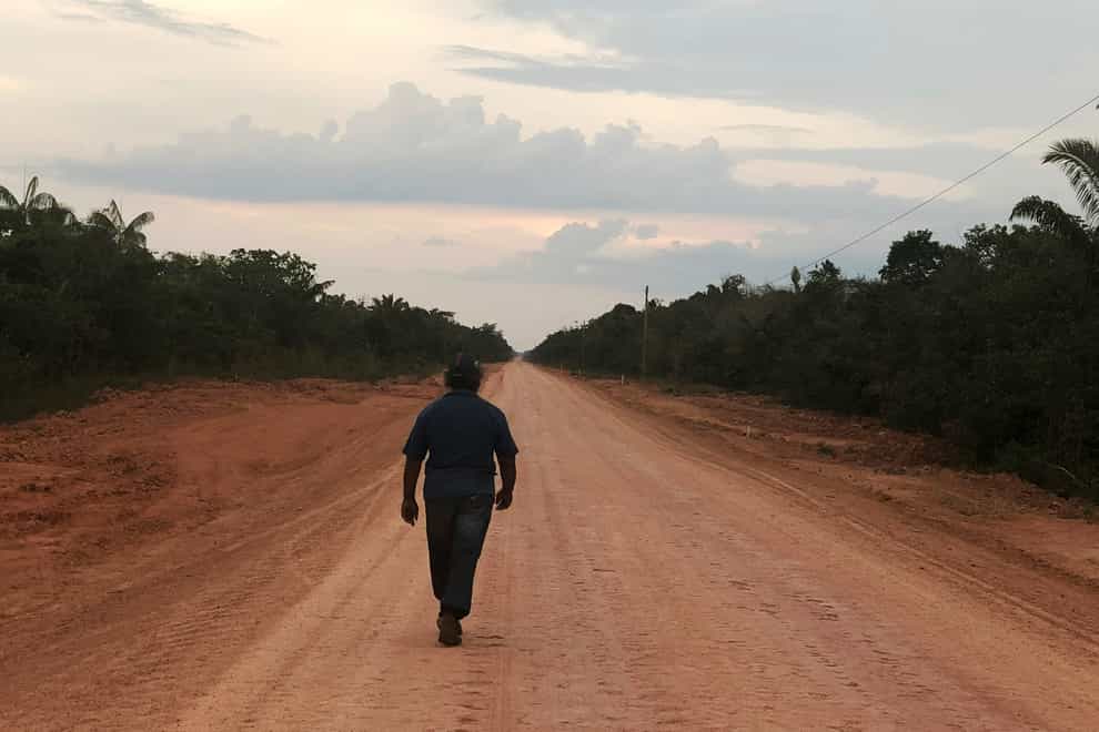 A man walks down an unpaved stretch of the BR-319 road in the Brazilian Amazon (Fabiano Maisonnave/AP)