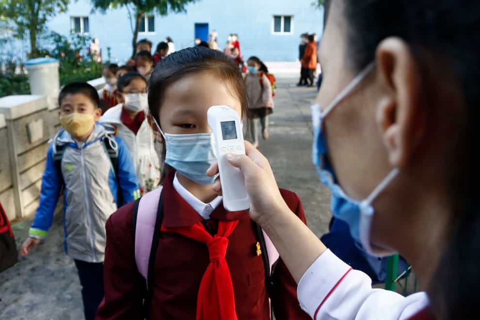 A teacher takes the temperature of a schoolgirl to help curb the spread of coronavirus at Kim Song Ju Primary School in Central District in Pyongyang (Cha Song Ho/AP)