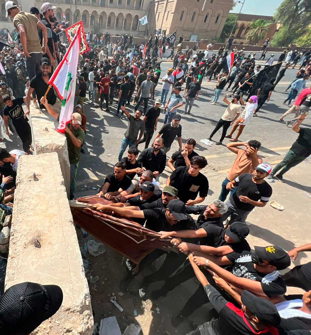 Protesters try to remove concrete barriers and cross the bridge towards the Green Zone area in Baghdad (Ali Abdul Hassan/AP)